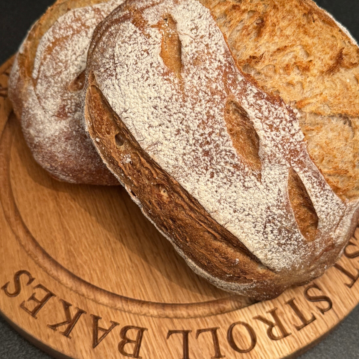 Loaves of bread on a wooden board with Forest Stroll Bakes' branding.